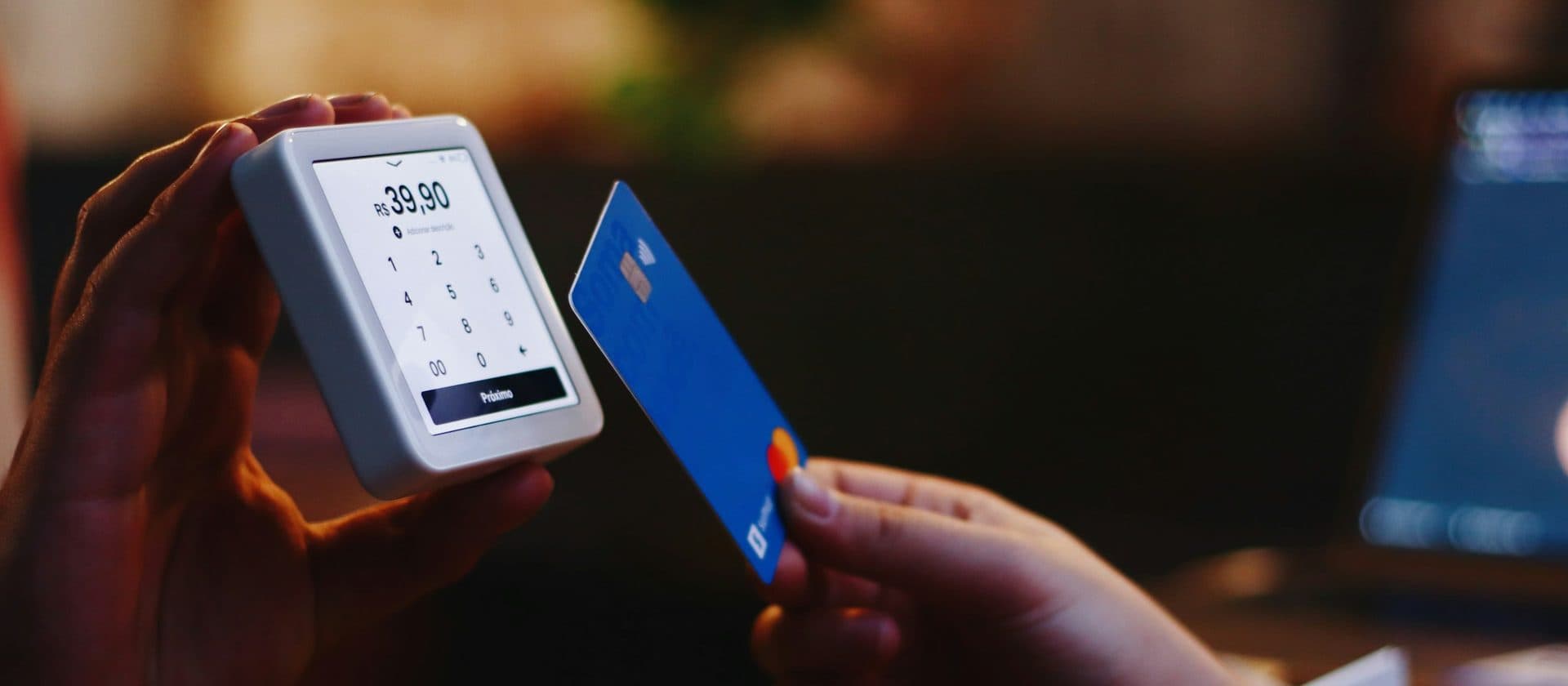 A contactless card held to a handheld payment reader, the amount lit on its screen.